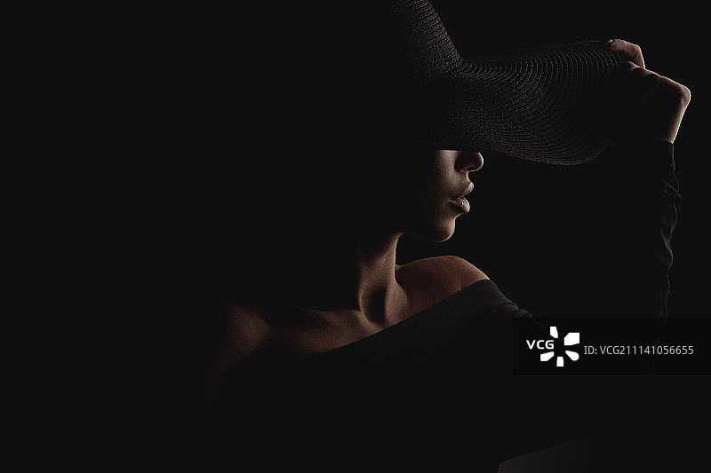 戴黑色宽檐帽的优雅奢华女性暗黑影棚人像图片素材