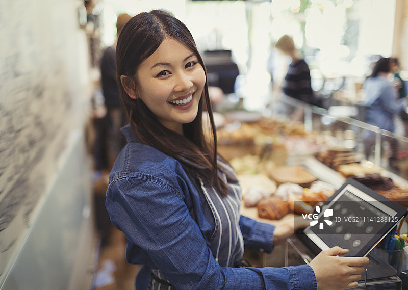 咖啡馆收银台前自信微笑的女收银员肖像图片素材