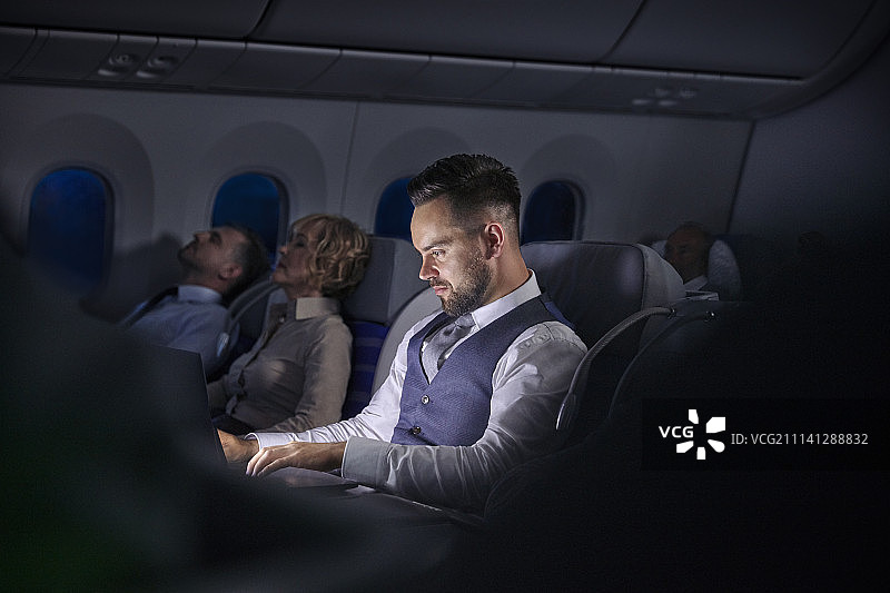 在夜间飞机的笔记本电脑工作的商人图片素材