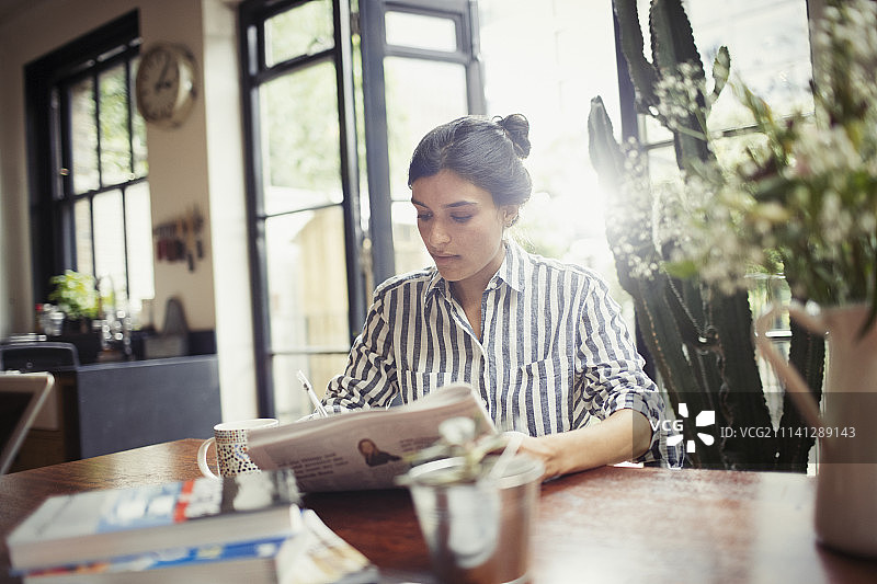 在餐厅看报纸的年轻女人图片素材