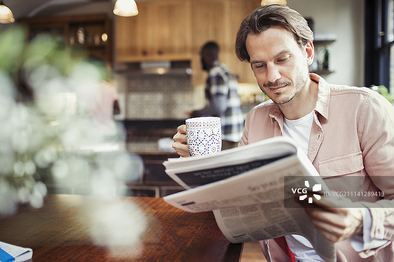 男人在厨房喝咖啡看报纸图片素材