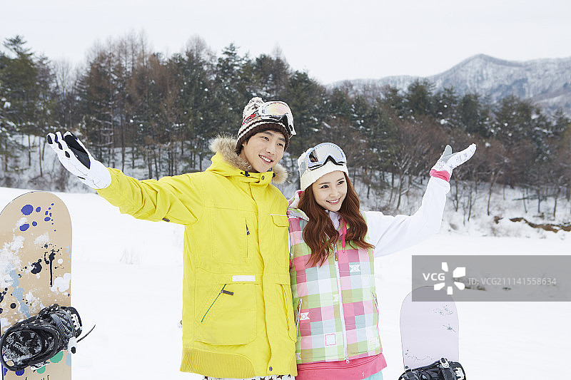 情侣穿着滑雪服站在雪地上的摄影照片图片素材