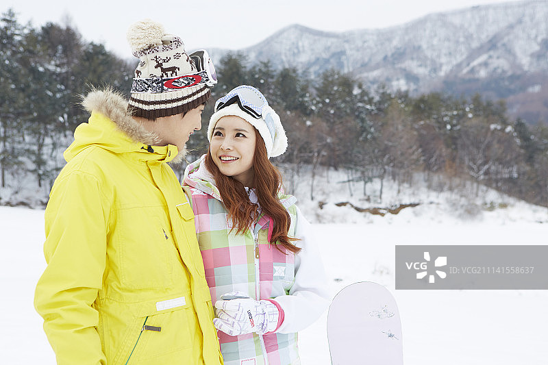 情侣穿着滑雪服站在雪地上的摄影照片图片素材