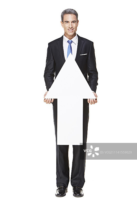 身穿西装、手持箭头符号的成熟男人的影棚照图片素材