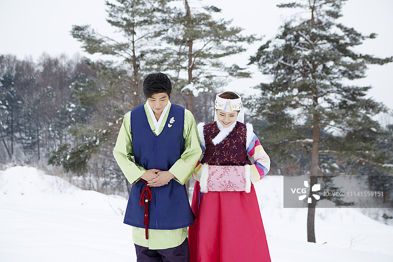 情侣身穿韩服站在雪地上问候的摄影照片图片素材