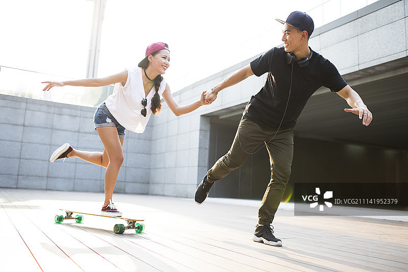 快乐的年轻情侣在滑滑板图片素材