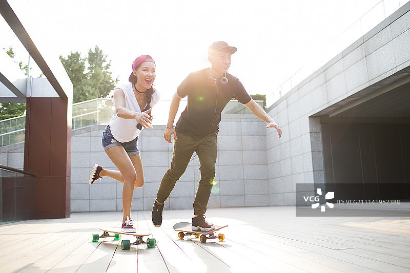 快乐的年轻情侣在滑滑板图片素材