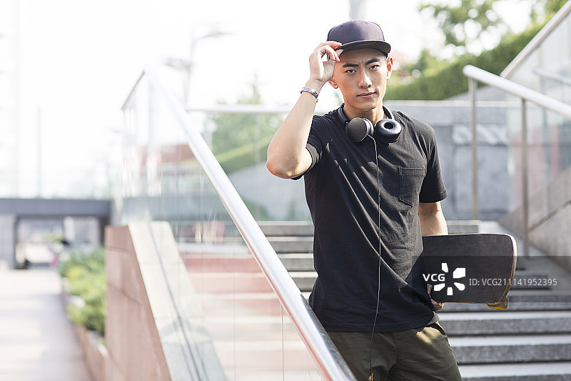 戴耳机的年轻男子手拿滑板图片素材