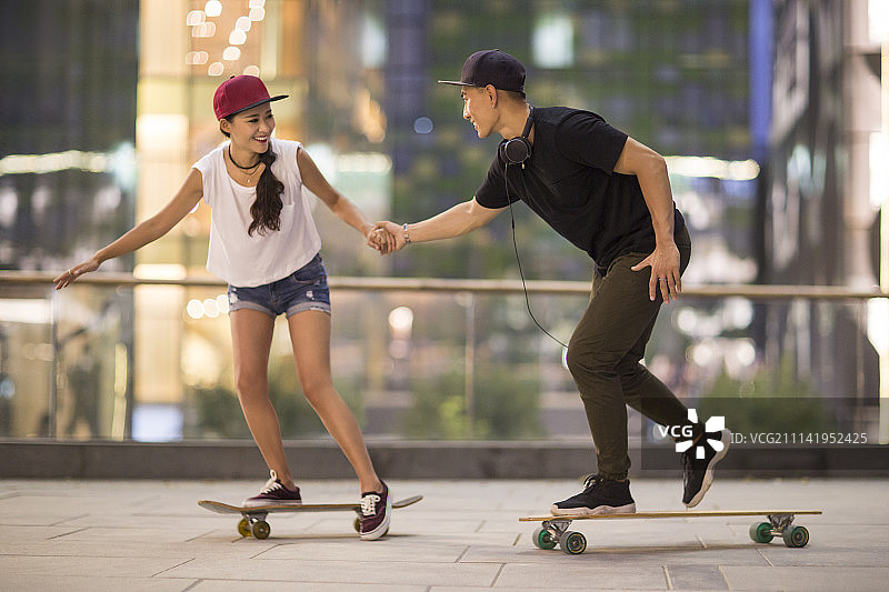 快乐年轻情侣在滑滑板图片素材