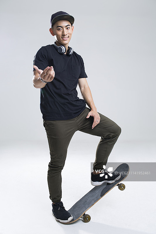 戴耳机的快乐年轻男子在滑滑板图片素材