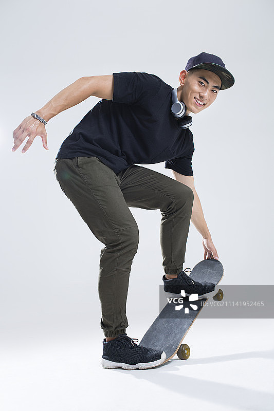 戴耳机的快乐年轻男子在滑滑板图片素材