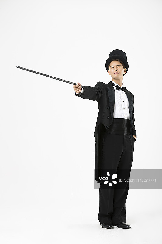 身穿魔术师服装的男人，手持手杖图片素材