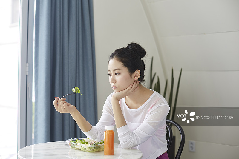 穿运动服在桌旁吃沙拉的女人图片素材