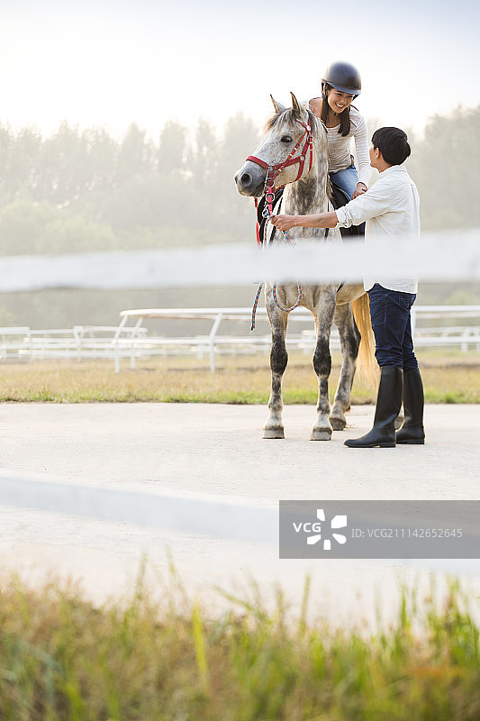 年轻情侣在马场骑马图片素材