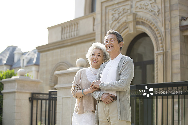 快乐的老年夫妇站在别墅前眺望远方图片素材
