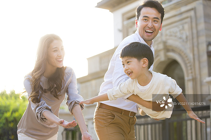 快乐的年轻家庭在别墅外玩耍图片素材