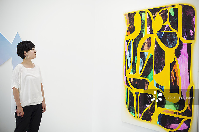 站在美术馆看现代画的白衬衫黑色短发女人图片素材