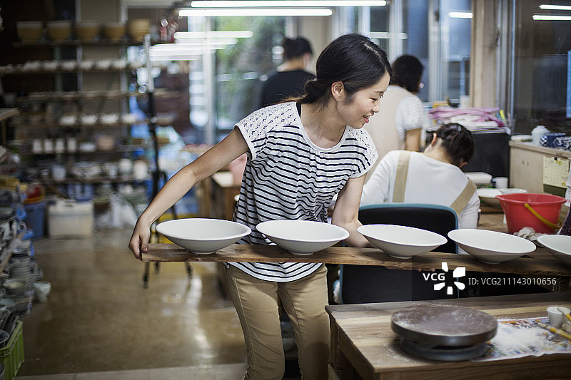 手捧木托盘站在日本瓷器工坊里的女人图片素材