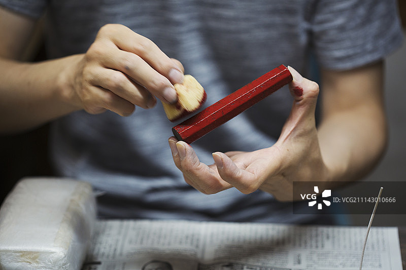 在日本瓷器作坊工作的女人特写，手持红色颜料棒和海绵图片素材