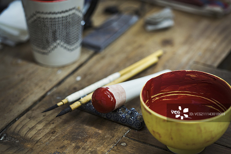 日本瓷器工坊内的材料特写：红漆碗、研杵和画笔图片素材