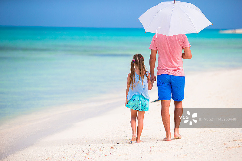 父亲和孩子在白色沙滩上散步图片素材