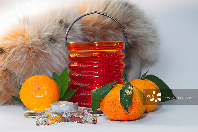 橘子、羽毛披肩和烛台上的蜡烛静物图片素材