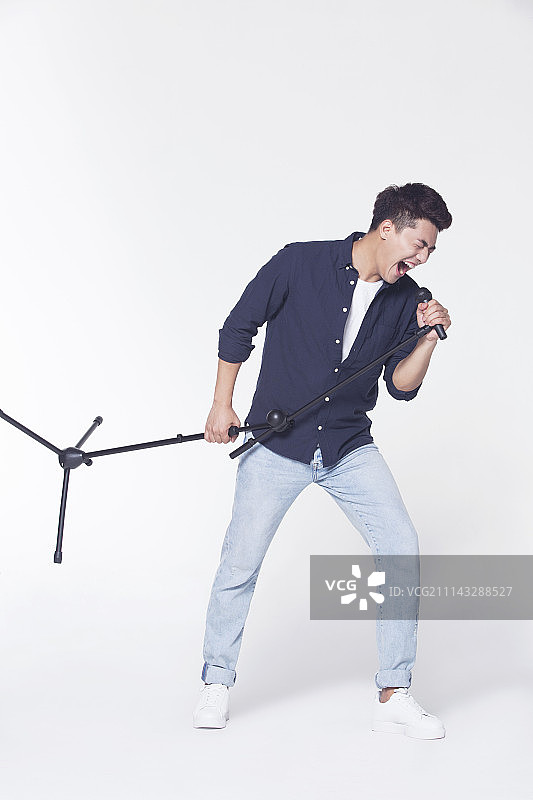 青年男子拿着麦克风唱歌图片素材
