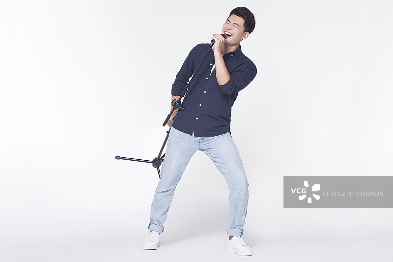 青年男子拿着麦克风唱歌图片素材