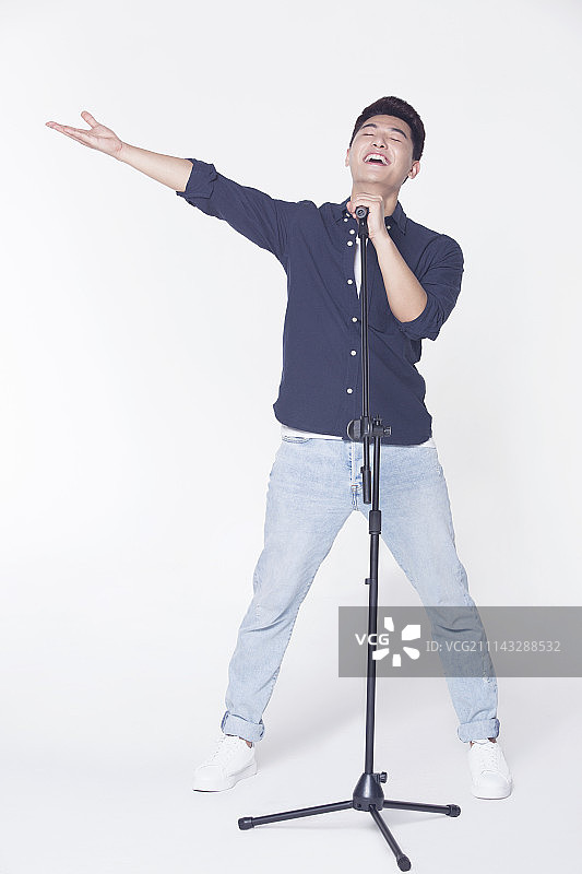 青年男子拿着麦克风唱歌图片素材