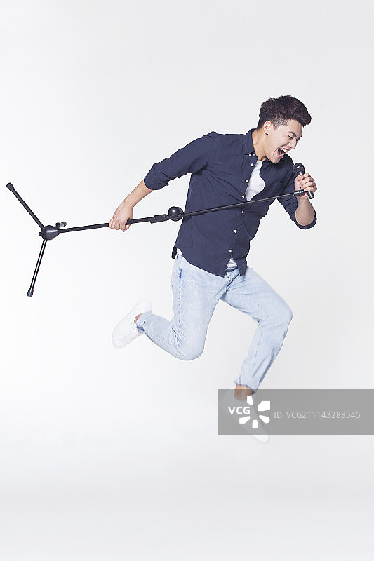 青年男子拿着麦克风唱歌图片素材