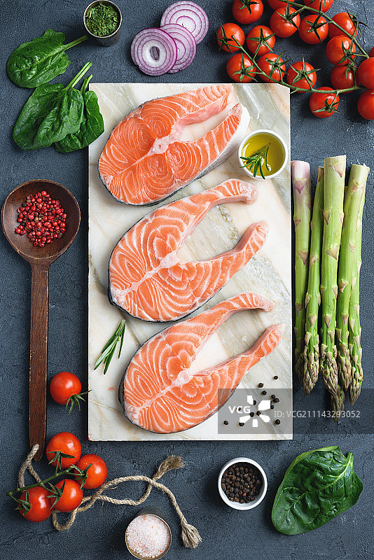 大理石背景上的新鲜三文鱼排、香草、橄榄油和烹饪配料图片素材