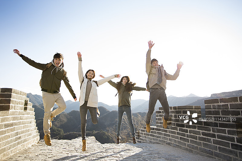 快乐年轻人在长城跳跃图片素材