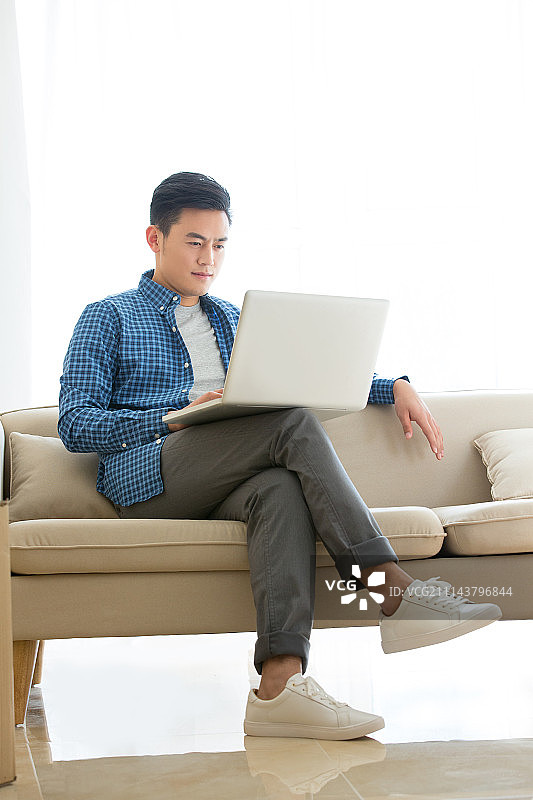 年轻男子在家里使用笔记本电脑图片素材