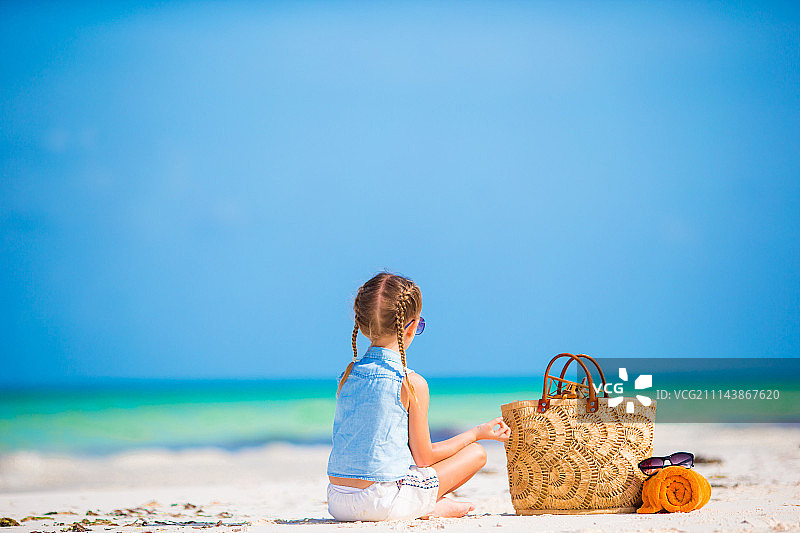 夏季假期里带着沙滩包和毛巾的可爱小女孩图片素材