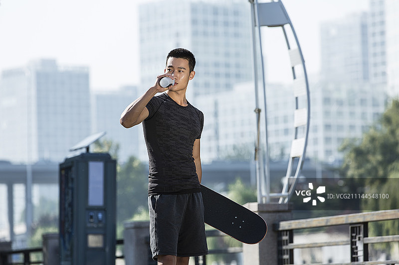 玩滑板的年轻男士运动后休息喝水图片素材