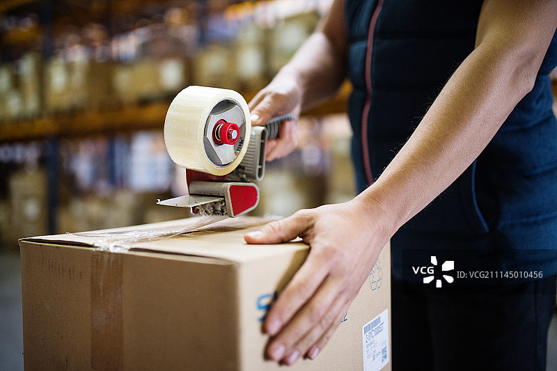 正在封纸箱的仓库男工人图片素材