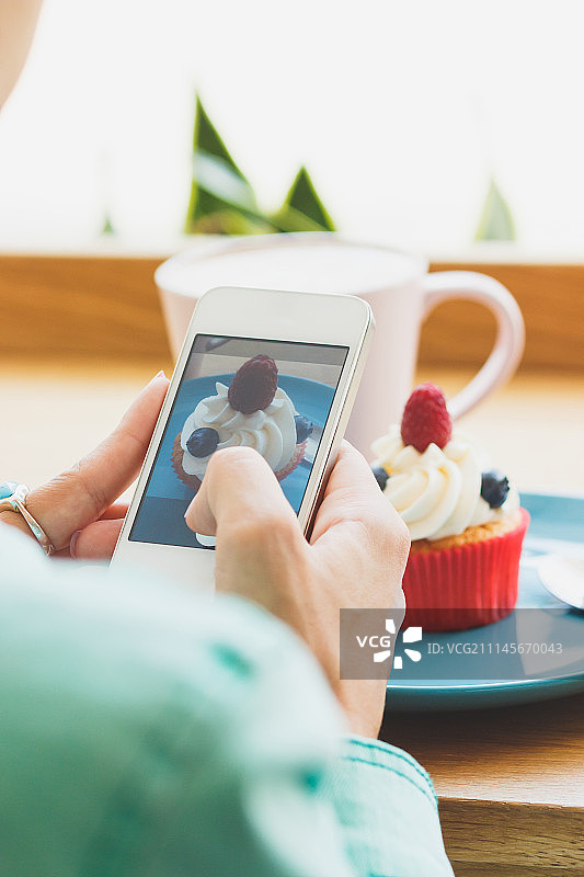 女人拍摄卡布奇诺咖啡杯和纸杯蛋糕图片素材