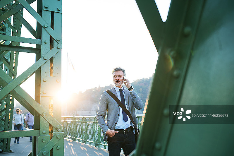 在城市里手持智能手机的中年商人图片素材