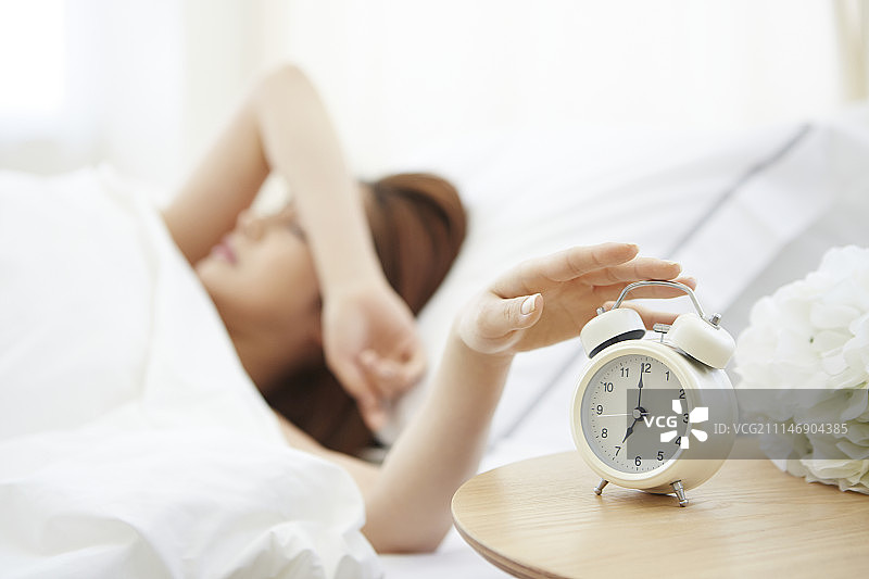 女子躺在床上拖动时钟的摄影作品图片素材