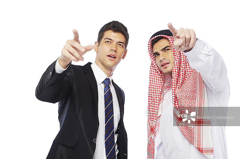 摄影棚拍摄的穿着西装的男人和穿着坎杜拉的男人指着图片素材