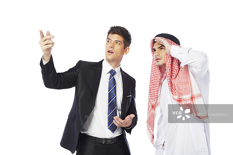 摄影棚拍摄的穿着西装的男人和穿着坎杜拉的男人指着图片素材