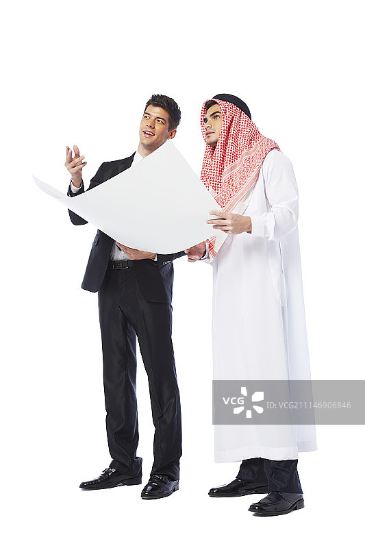 身穿西装的男人和身穿坎杜拉的男人在影棚中看蓝图图片素材