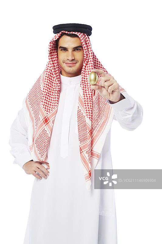 男子身穿坎杜拉长袍手持金蛋拍摄图片素材