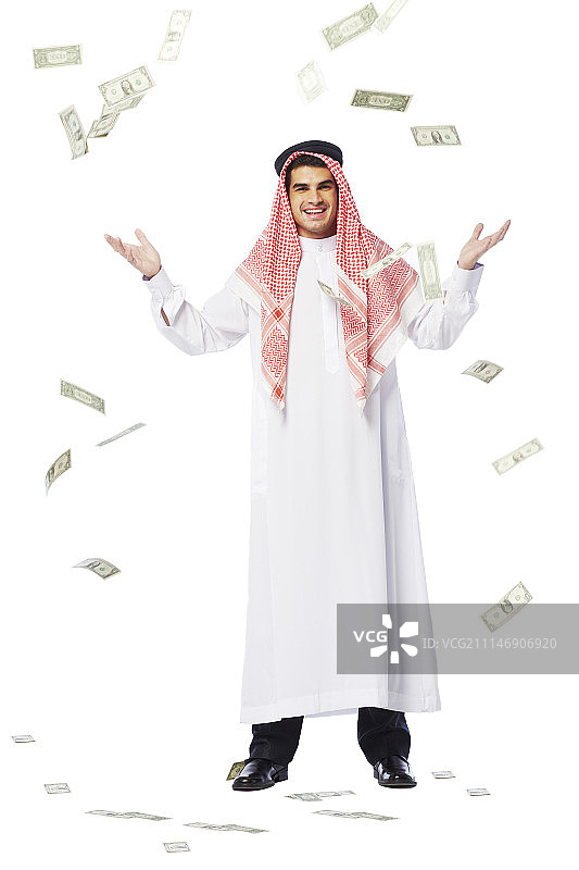 穿着坎杜拉的男人张开双臂看着钱落下的影棚照片图片素材