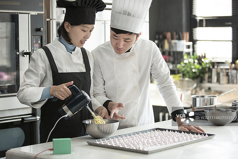 男糕点师指导女糕点师制作甜点心图片素材