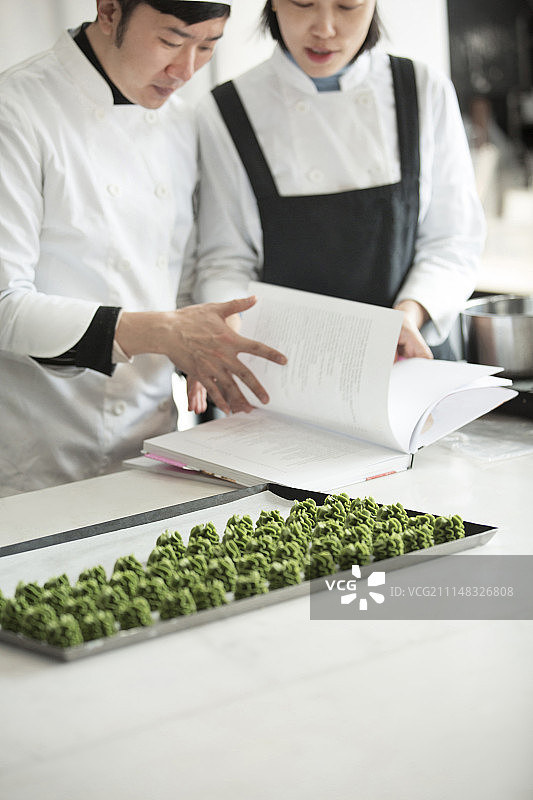 男、女厨师在厨房研究学习制作甜点心图片素材