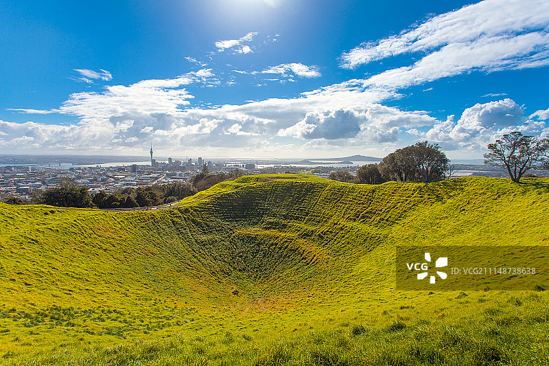 草地覆盖的火山口公园与城市天际线图片素材