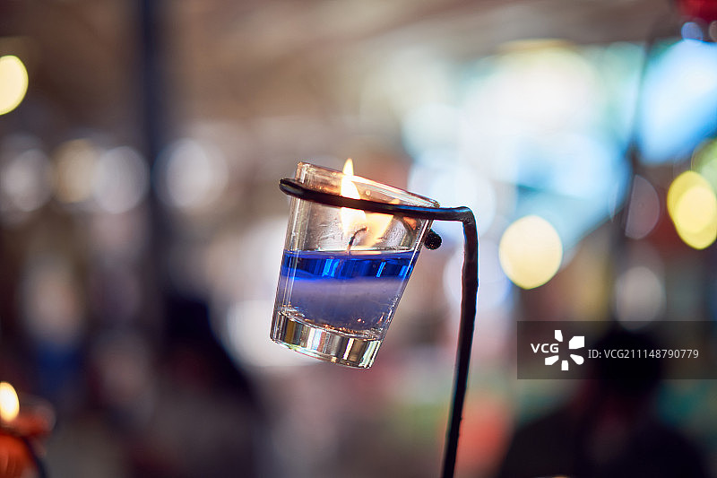 玻璃杯中的蓝色蜡烛和散景背景（主体已模糊）图片素材