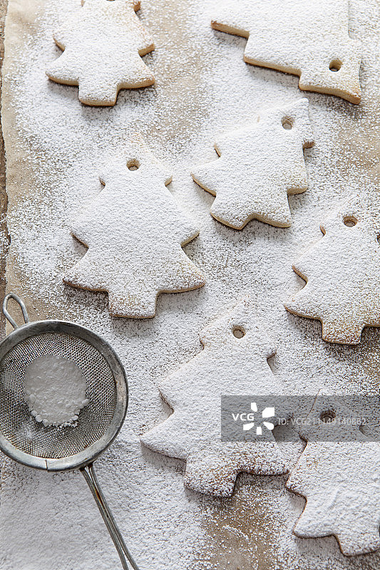 棕色烘焙纸上，复古迷你筛子筛出的糖粉，七个树形饼干图片素材