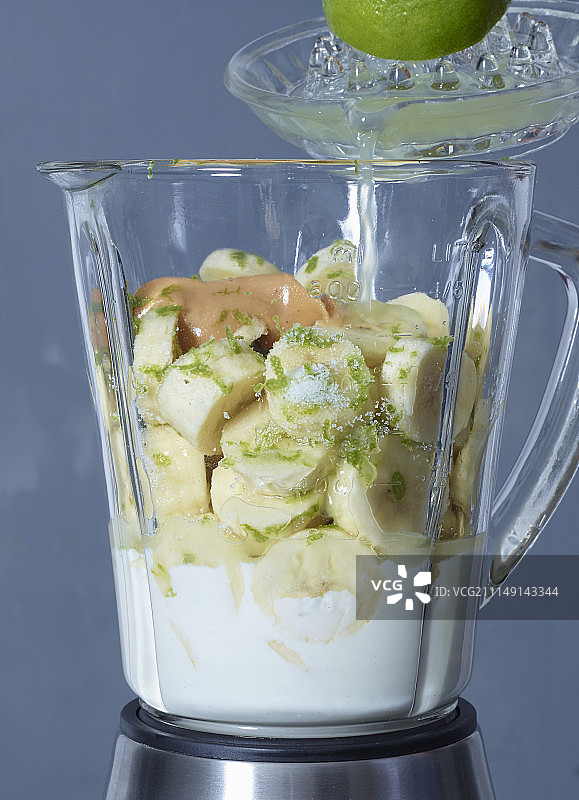 冻酸奶与香蕉、青柠和花生酱的食材在搅拌机里图片素材